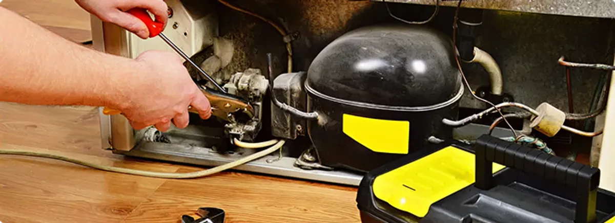Refrigerator repair technician fixing the compressor and wiring in Broken Arrow, OK
