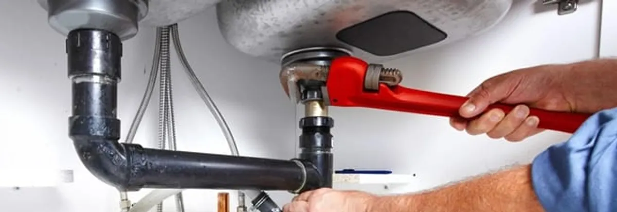 Garbage disposal repair technician tightening the sink drain and disposal connection in Tulsa, OK