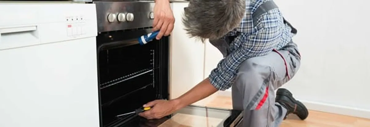 Oven repair technician inspecting and servicing an electric oven in Tulsa, OK