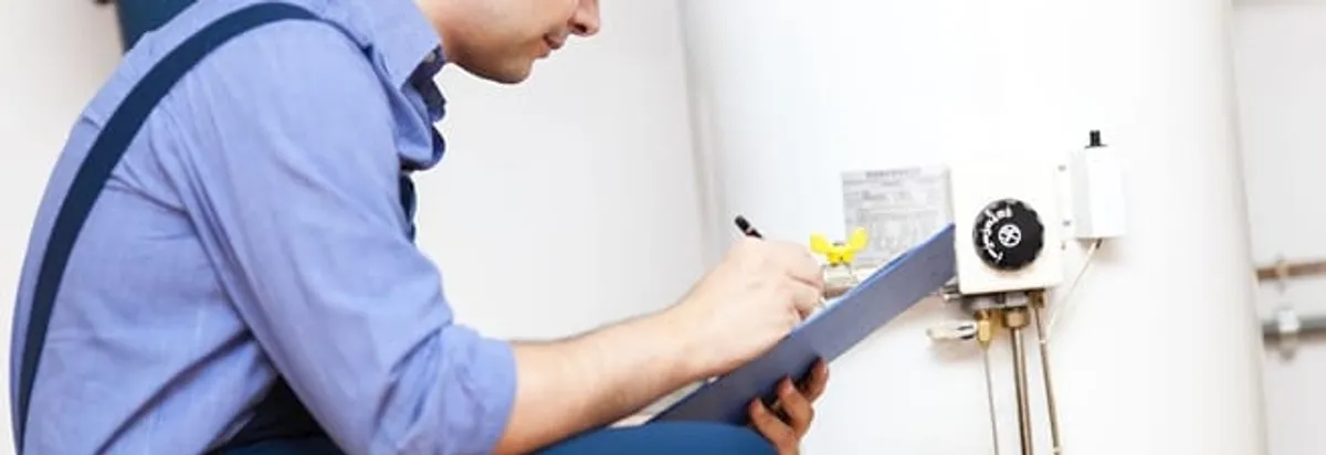 Water heater repair technician inspecting the unit and recording service notes in Tulsa, OK
